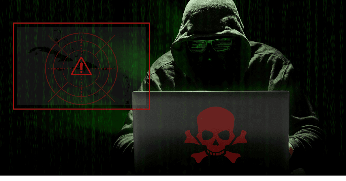 Hacker in dark hoodie using laptop with red skull icon, symbolizing ransomware threats targeting Caribbean businesses